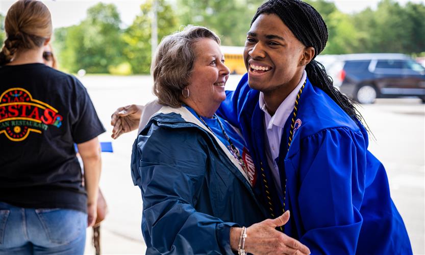 A senior hugs an elementary school teacher